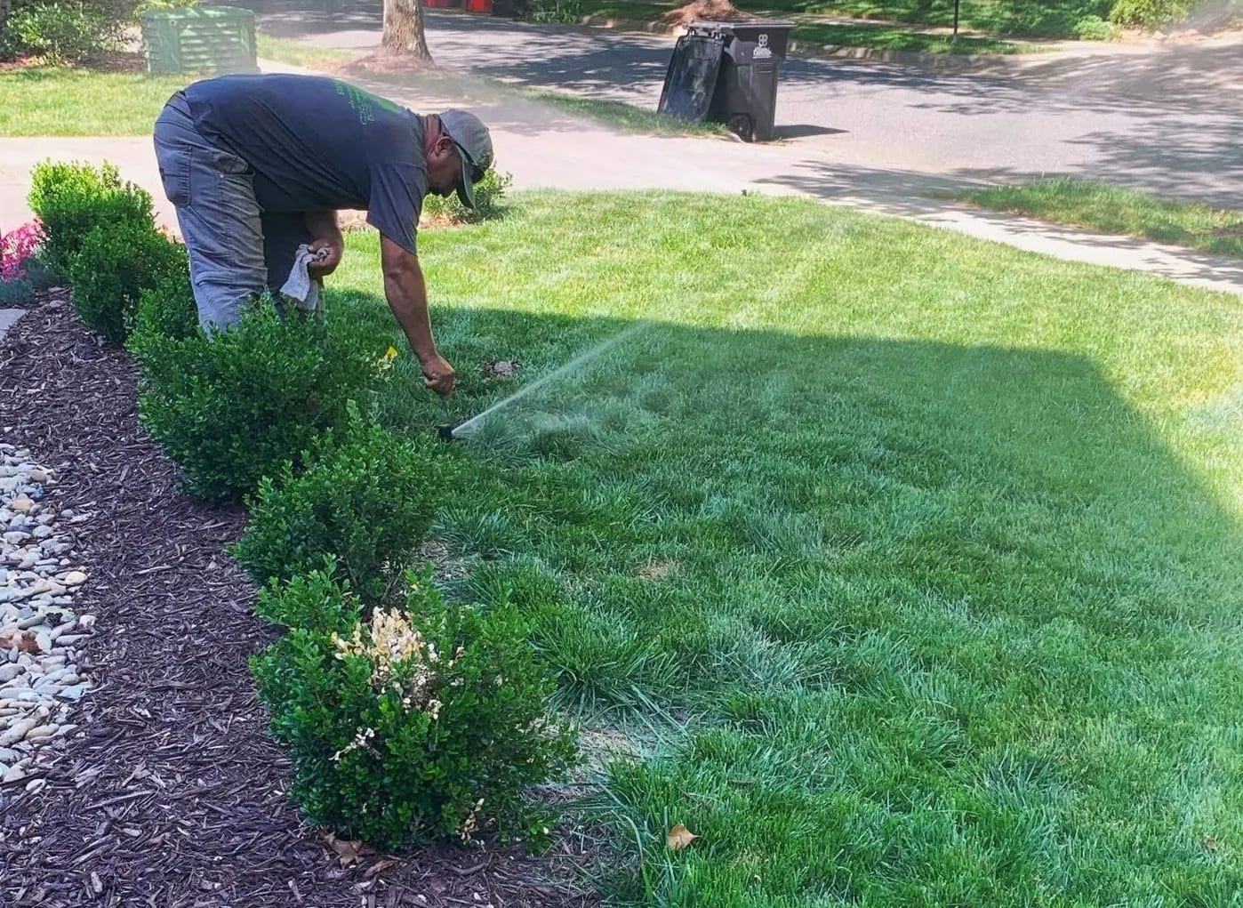 Crew member adjusting a sprinkler head while the zone runs