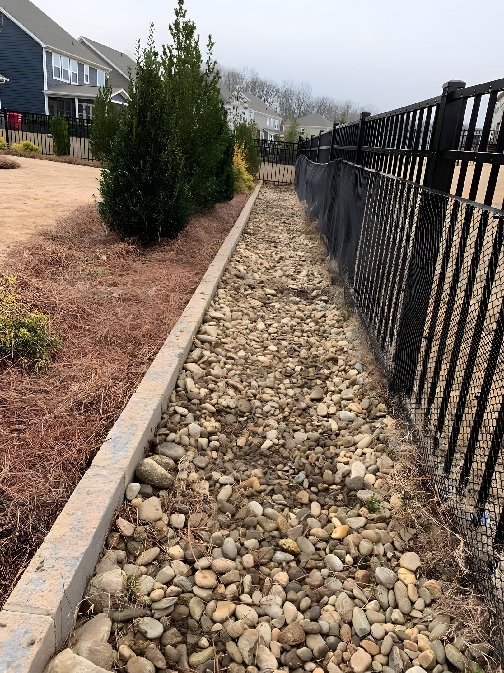 River rock drainage channel routing water through a lawn
