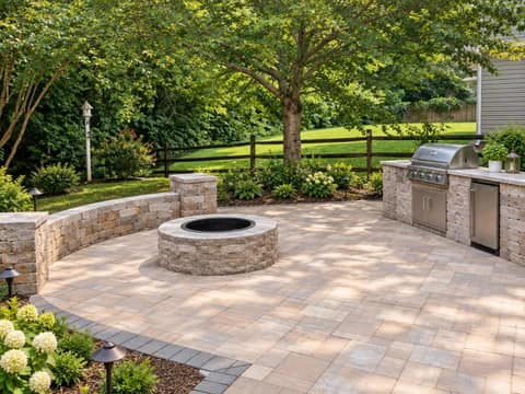 Stone grill island with built-in grill and fridge beside a fire pit patio