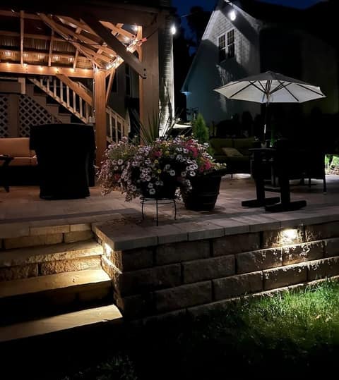 Pergola string lights and lit stone steps and wall at night