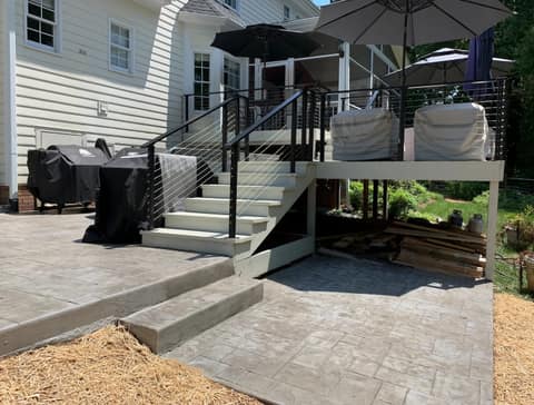 Two-level stamped concrete patio below a deck with cable railing