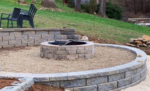Curved block retaining wall around a gravel fire pit terrace